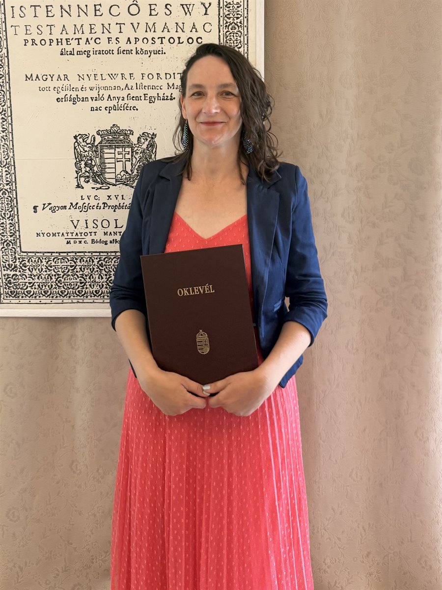 Nagy Ilona a lelkigondozói oklevelével, a vizsolyi Biblia címlapja előtt